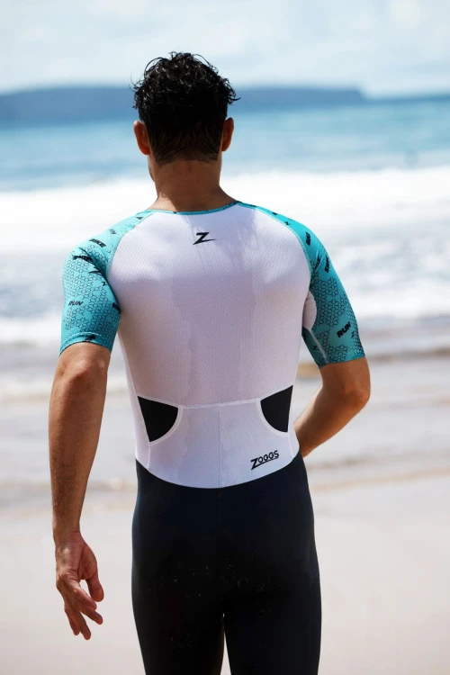 Strój-triathlonowy-turkusowo-biały-mężczyzna-stojący-tyłem-na-plaży.jpg