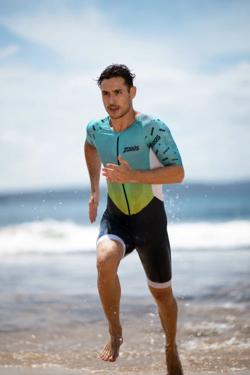 Strój-triathlonowy-turkusowo-biały-mężczyzna-biegnacy-po-plaży-zbliżenie.jpg