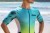 Strój-triathlonowy-turkusowo-biały-mężczyzna-stojący-przodem-na-plazy-tors.jpg