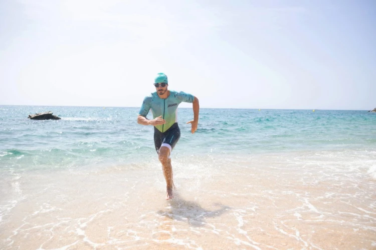 Strój-triathlonowy-turkusowo-biały-mężczyzna-biegnący-po-plaży.jpg